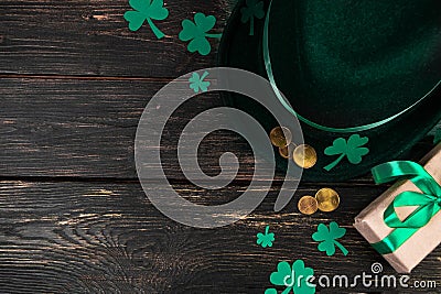 Leprechaun hat, gold coins, clover shamrock and green ribbon gift on dark wooden background. Good luck symbols for Stock Photo