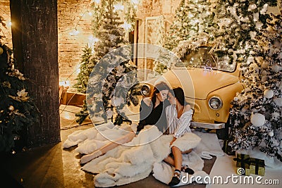 Lesbian couple hugs against background of Christmas decorations and retro car Stock Photo