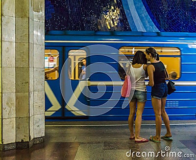 Lesbian couple standing on underground station on background of riding train Editorial Stock Photo