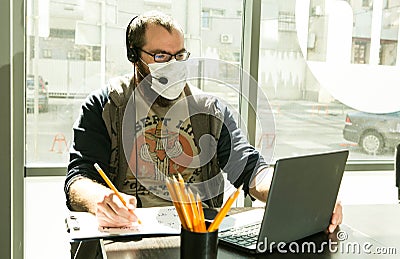 Lesson. Foreign language teachers discuss online quarantine lessons. A man in a medical mask in a classroom are sitting at a table Stock Photo