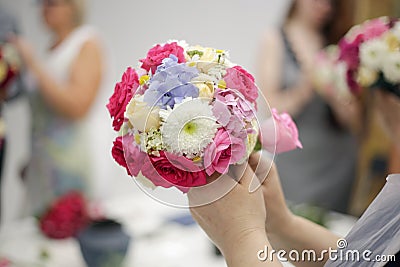 lesson on making a wedding bouquet in the shape of a ball. A young woman makes a bouquet of freshly cut bright flowers. Stock Photo