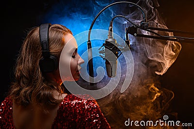 Lesson and training in vocal and singing. A girl sings into a microphone, bright background Stock Photo