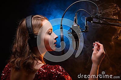 Lesson and training in vocal and singing. A girl sings into a microphone, bright background Stock Photo