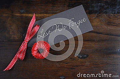 Lest We Forget, Red Poppy Lapel Pin Badge on dark recycled wood Stock Photo