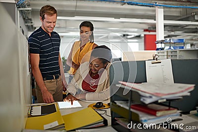 Let me show you my latest design. a three work colleagues talking together over a digital tablet. Stock Photo