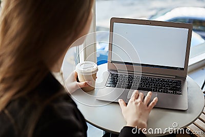 Let uf check last news. Indoor rearview of stylish woman sitting in cafe, drinking cup of coffee and working with laptop Stock Photo