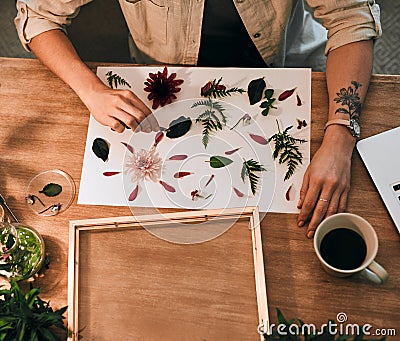Let your creativity run the show. an unrecognizable florist decorating and pressing flowers into a wall frame inside her Stock Photo