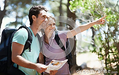 Lets explore that trail. A happy young couple backpacking through the woods. Stock Photo