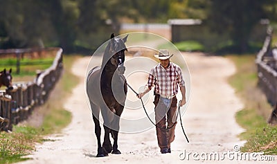 Lets go for a talk. Shot of a cowboy leading his horse by the reins. Stock Photo