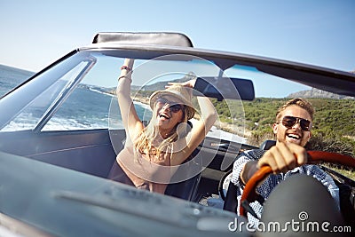 Lets just keep driving. A happy young couple driving in a convertible on a bright summers day. Stock Photo