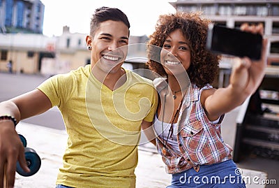 Lets take a selfie. A young couple taking a selfie while out skateboarding. Stock Photo