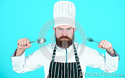 Lets try dish. Hungry chef ready to try food. Time to try taste. Chef serious strict face hold spoon and fork. Man Stock Photo