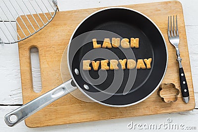 Letter cookies word LAUGH EVERYDAY and kitchen utensils Stock Photo