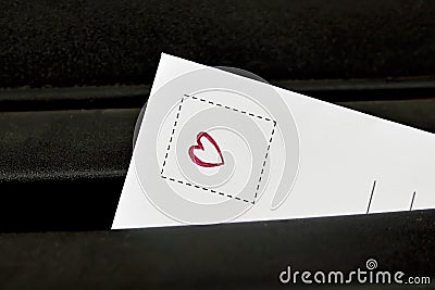 A letter with a drawing of a red heart tucked into the black postbox. Stock Photo