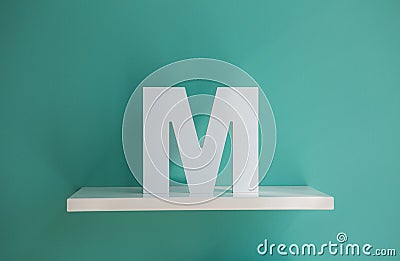 Letter M turquoise color on a white shelf Stock Photo