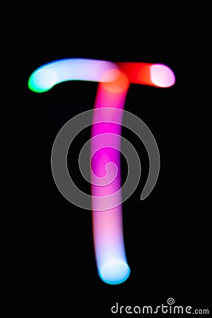 Letter T. Glowing letters on dark background. Abstract light painting at night. Creative artistic colorful bokeh. New Year. Stock Photo