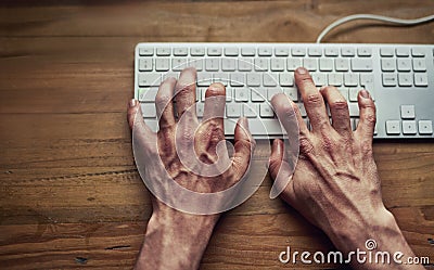 Letting his fingers do the talking. High angle shot of an unidentifiable man typing on a computer keyboard at night. Stock Photo