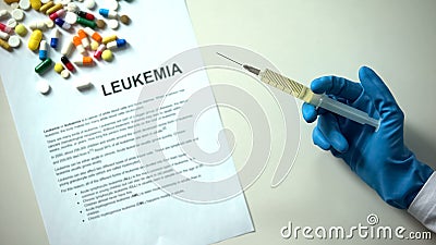 Leukemia diagnosis on paper, doc hand with syringe, pills and tablets on table Stock Photo