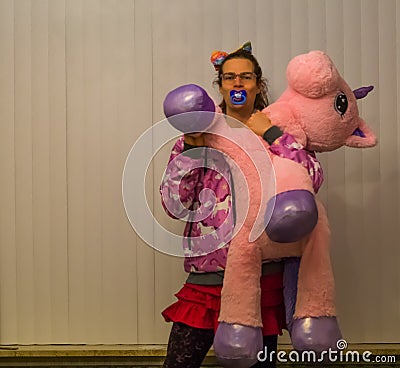 LGBT diversity, Cute transgender girl holding a pink stuffed animal and sucking on a pacifier, Adult Infantilism, Autism and Stock Photo