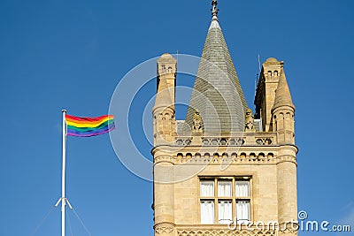 LGBT flag seen flying next to a historical, UK University campus gothic tower. Editorial Stock Photo