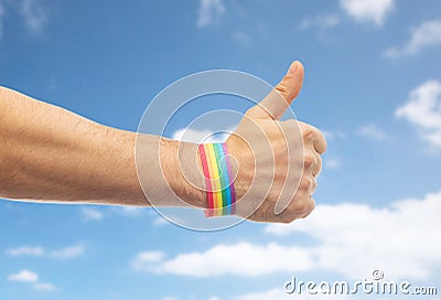 Hand with gay pride rainbow wristband shows thumb Stock Photo