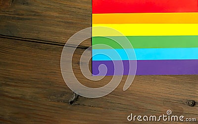 LGBTQ community flag on a wooden background. On the wooden table there is a symbol of LGBT freedom. Stock Photo