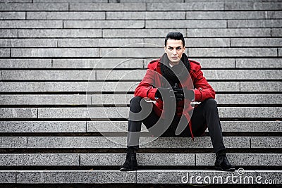 LGBTQ community lifestyle concept. Young homosexual man sits on a stairs. Handsome fashionable gay male model poses in Stock Photo