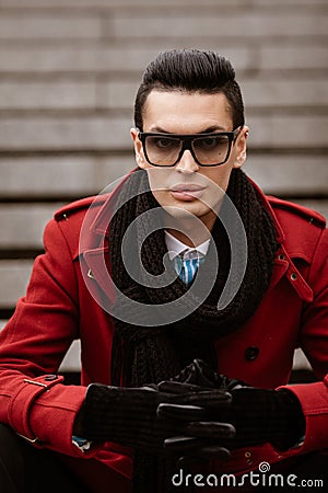 LGBTQ community lifestyle concept. Young homosexual man sits on a stairs. Handsome fashionable gay male model poses in Stock Photo