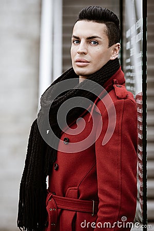 LGBTQ community lifestyle concept. Young homosexual man stands near glass. Handsome fashionable gay male model poses in Stock Photo