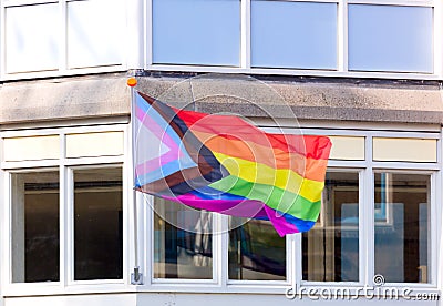 LGBTQ rainbow flag is flown on the facade of the building. City street. Equal rights. Amsterdam, Netherlands, Europe Stock Photo