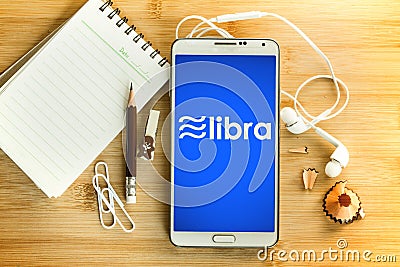 Libra coin cryptocurrency and block chain symbol and notepad with pencil and smart phone on wooden table , a New digital Editorial Stock Photo