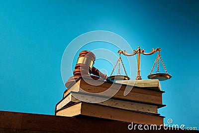 libra scale and gavel hammer on stack of books against blue background Stock Photo