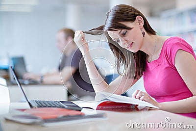 In the library - pretty female student with laptop and books Stock Photo