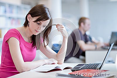 In the library - pretty female student with laptop and books Stock Photo