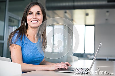 In the library - pretty female student with laptop and books Stock Photo