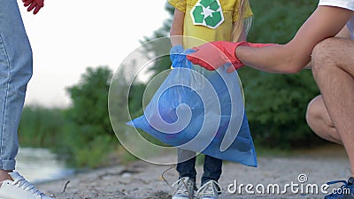 Liefdadigheid het schoonmaken, jonge familie met weinig jong geitje in rubberhandschoenen verzamelt afval in vuilniszak op vuil s stock video Liefdadigheid het schoonmaken, jonge familie met weinig jong geitje in rubberhandschoenen verzamelt afval in vuilniszak op vuil s stock video