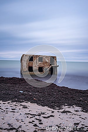 Liepaja beach bunker. Brick house, soft water, waves and rocks. Abandoned military ruins facilities in a stormy sea. Stock Photo