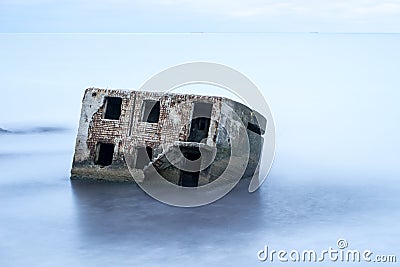 Liepaja beach bunker. Brick house, soft water, waves and rocks. Abandoned military ruins facilities in a stormy sea. Stock Photo