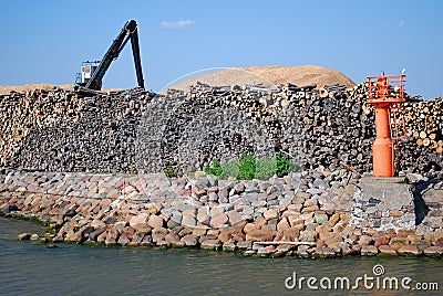 Liepaja, Latvia - May 31, 2011: Port with mole, lighthouse, logs and logging crane Editorial Stock Photo