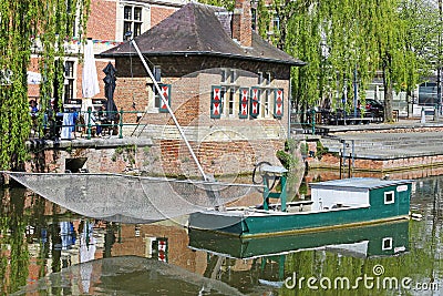 View on water moat with old traditional eel net fishing boat, medieval houses and weeping willow trees background Stock Photo