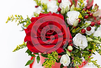 Life-affirming composition of fresh flowers Rose, Eustoma, Solidaga, Pistachio leaves and decorative berries in a scarlet cardbo Stock Photo