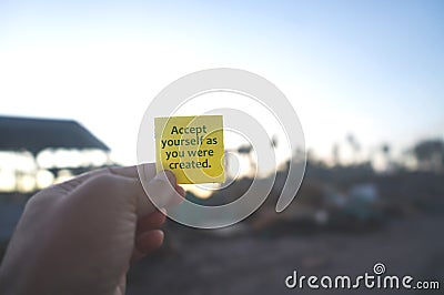 Life inspirational and motivational quote - Accept yourself as you were created. With person holding yellow card in hand. Stock Photo