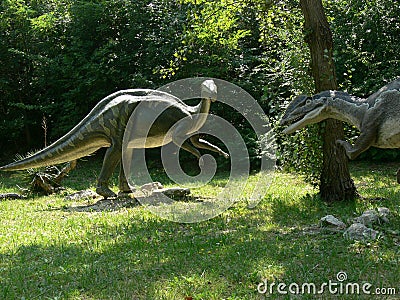 Predator dinosaur lurking to attack an iguanodon in the wood of the Extinction Park in Italy Editorial Stock Photo
