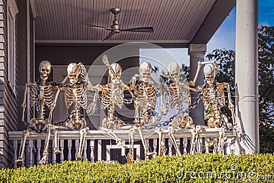 Life sized Skeleton Chain Gang sits on banister of vintage home porch - Halloween decoration Stock Photo