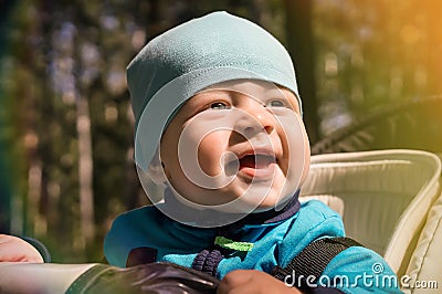 Life style close-up portrait baby boy little sits in a stroller and smiles, sunny day Stock Photo