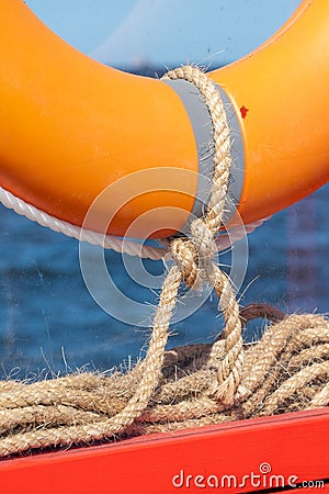 A lifebuoy is attached to a bright orange wooden frame with linen ropes Stock Photo