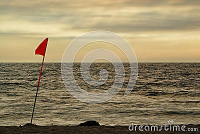 A lifeguard`s flag in the afternoon light of an overcast beach. Stock Photo