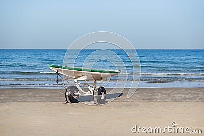Lifeguard surf rescue surfboard with oars on the stand with wheels on sand beach close the sea. Stock Photo