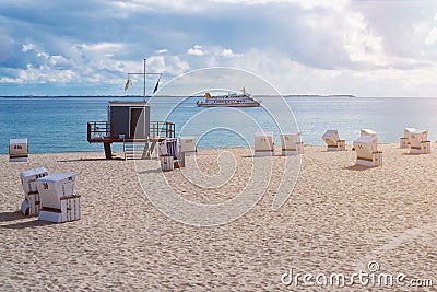 Lifeguard tower on sandy beach on the island of Sylt, Germany with ship on ocean Stock Photo