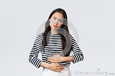Lifestyle, beauty and fashion, people emotions concept. Woman got food poisoned, touching belly feeling unwell. Asian Stock Photo